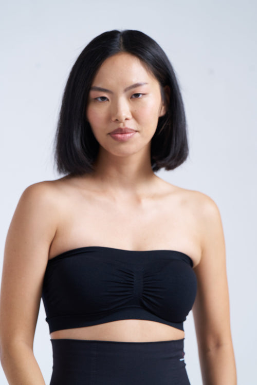 This image features a woman modeling the Munns & Mars Seamless Tube Bra in a striking black color. The tube bra boasts a strapless design, making it ideal for wearing with strapless or off-shoulder outfits.